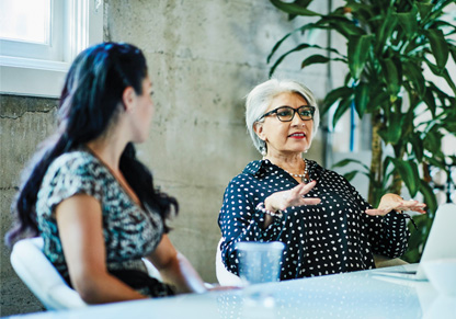 An older and younger woman sat a table talking. 