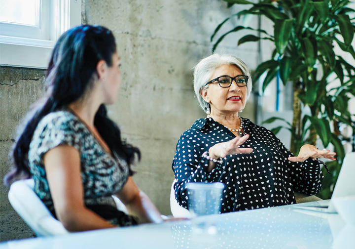 An older and younger woman sat a table talking. 
