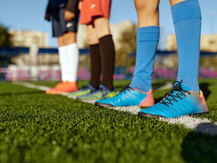 Close up of three teenage Fútbol players standing at a white line on a turf Fútbol field