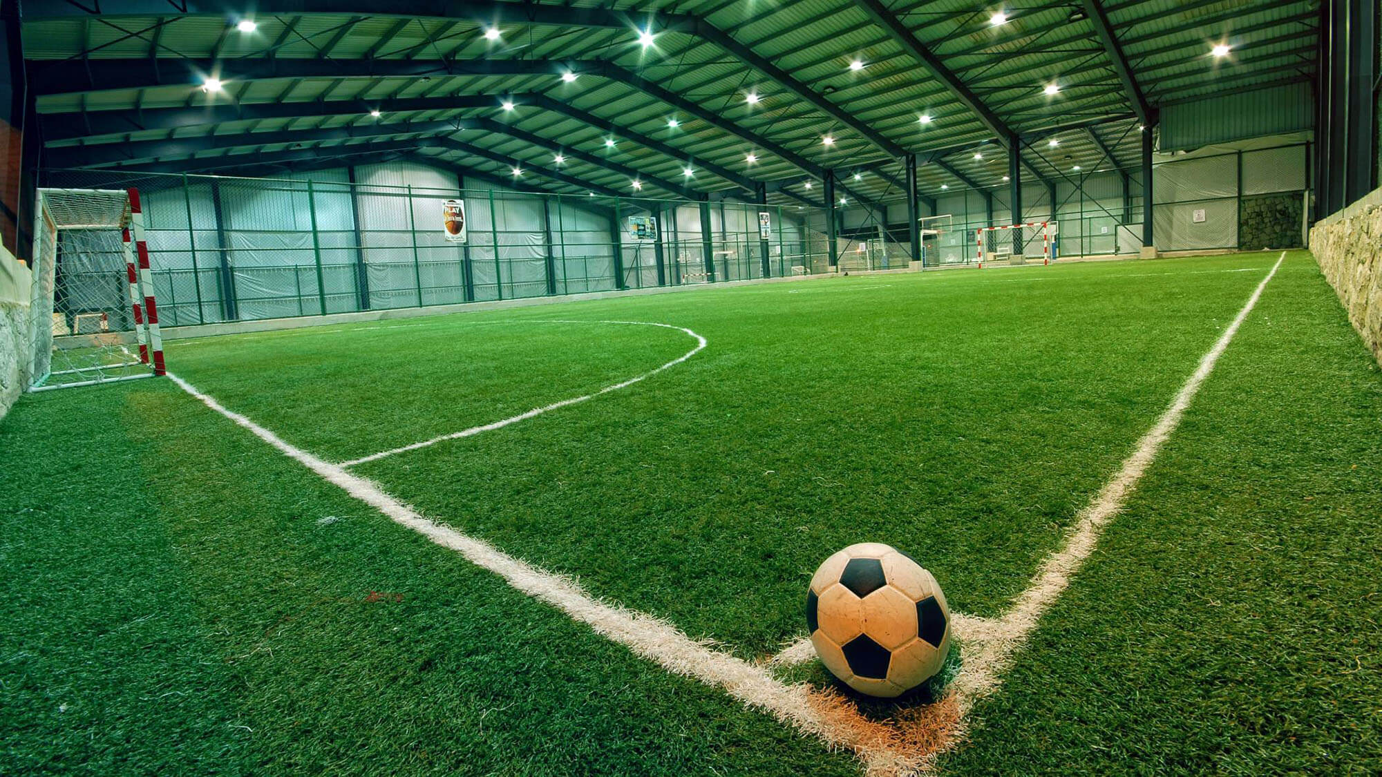 soccer ball sitting at the corner of an indoor soccer field