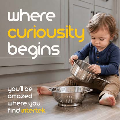 An infant sitting on the kitchen floor playing with a metal pot